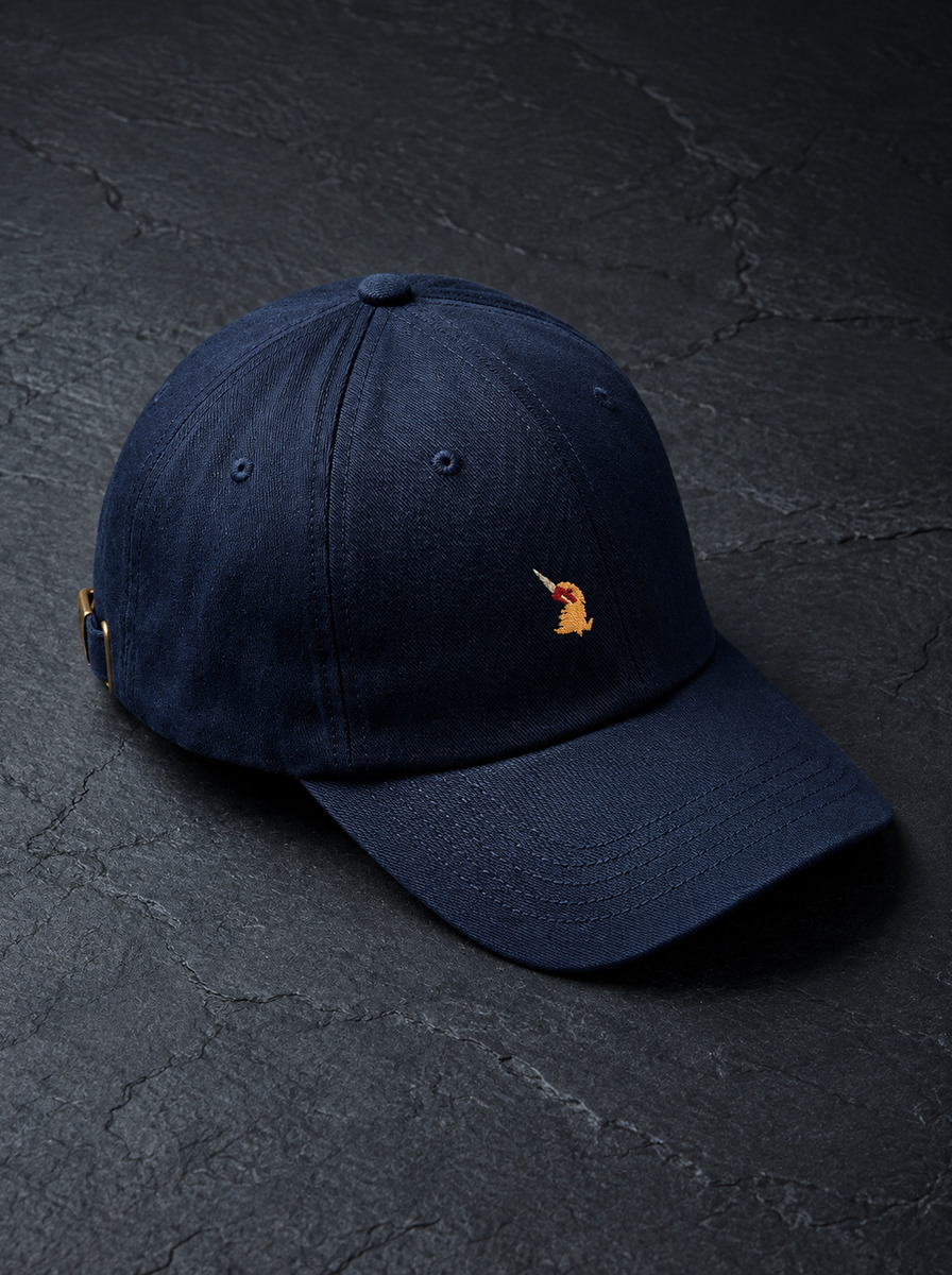 An unstructured six-panel cap in navy twill on dark slate, the embroidered bird on the front panel.