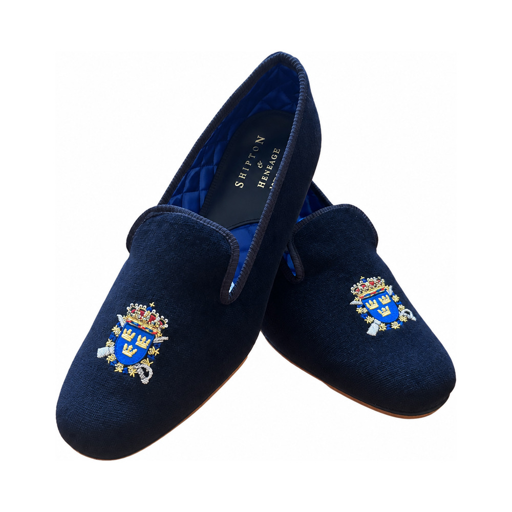 The Albert slipper in black velvet, three gold crowns on a blue shield beneath a royal crown embroidered on the vamp, blue quilted lining.